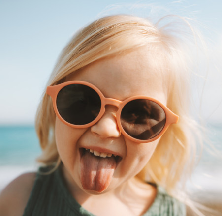 Une petite fille portant des lunettes de soleil tire la langue.