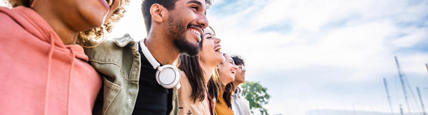 Cinq jeunes en extérieur se tiennent par les épaules.