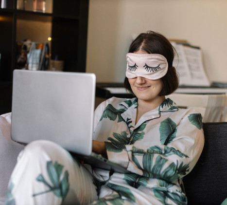Une femme porte un bandeau sur ses yeux et regarde un ordinateur portable